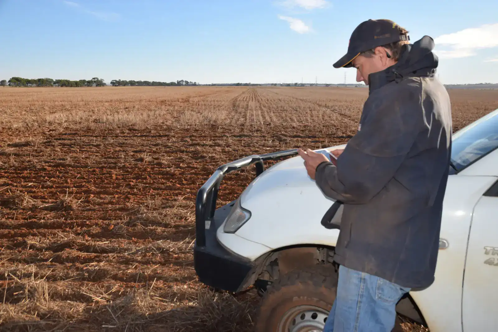 Australian farmer reviewing his farm numbers on a tablet in the paddock - understand your farm numbers with P2PAgri
